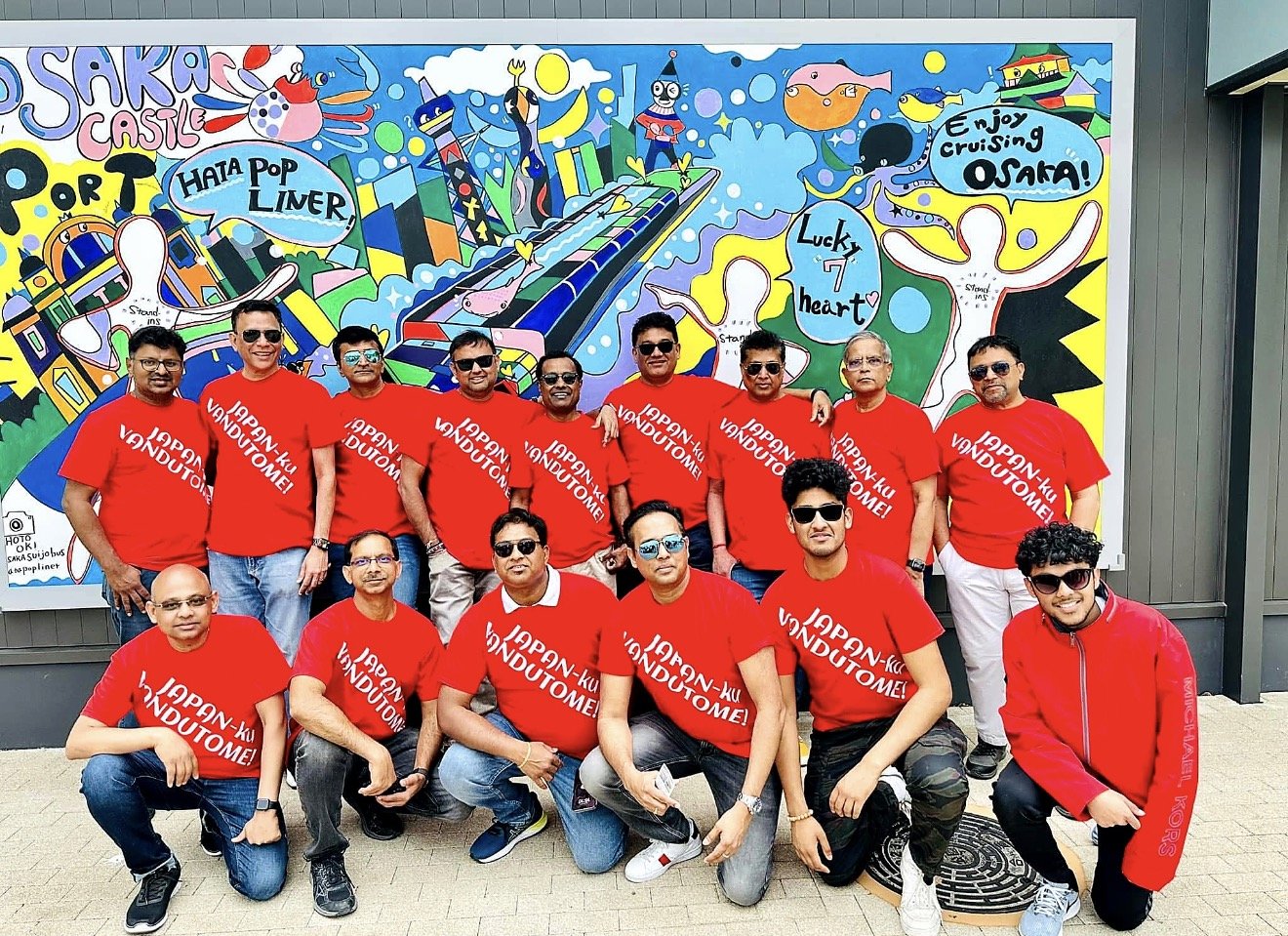 Group in matching red shirts in front of a mural